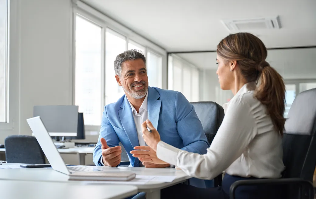 Two colleagues talking through a project at a desk