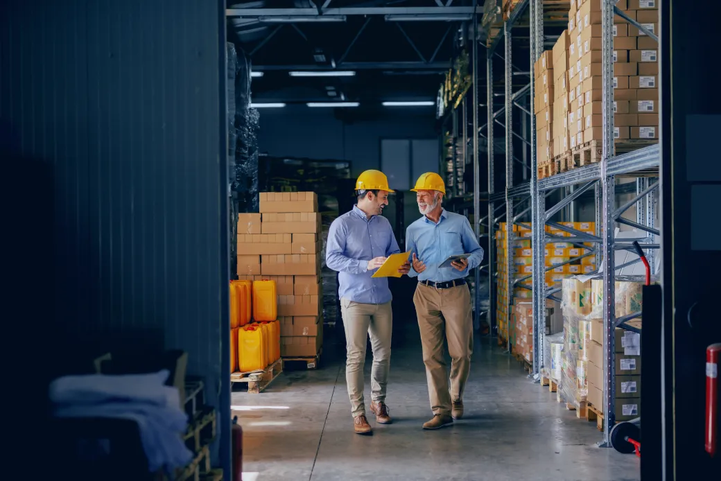 Two supervisors walking a warehouse aisle with a tablet