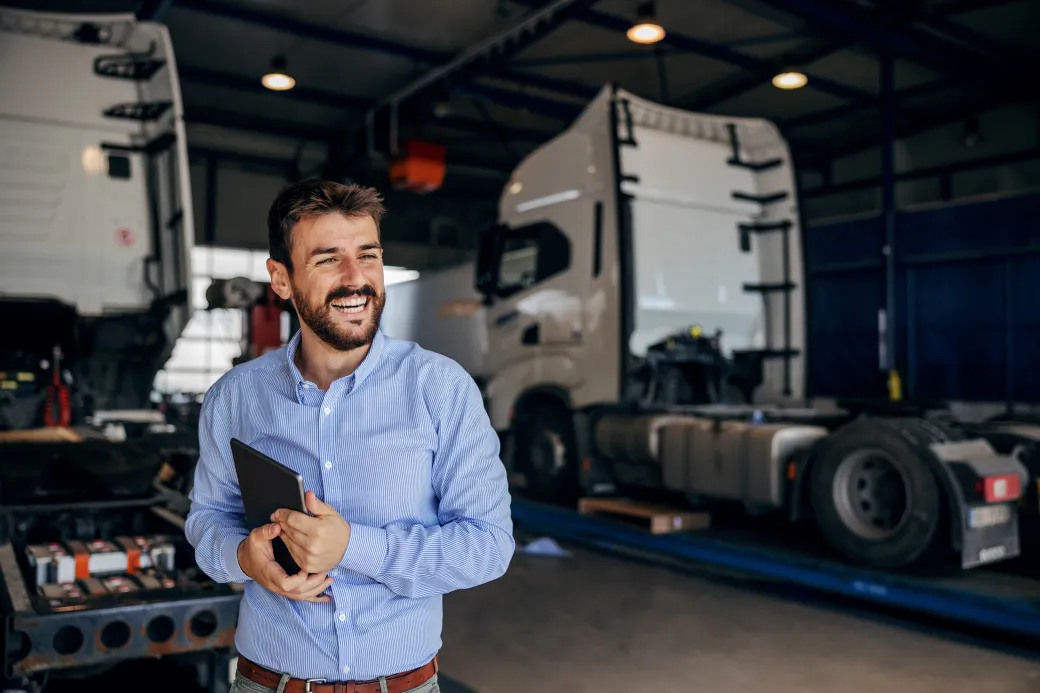 A fleet supervisor with a tablet in front of service trucks