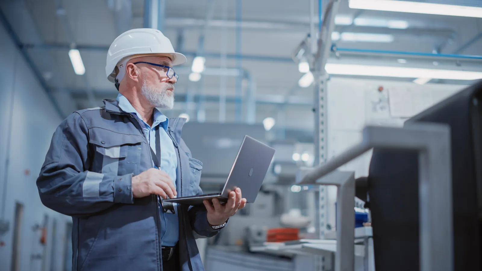 SAP Cloud ERP consultant reviewing operations on a laptop in a manufacturing plant